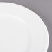 A Libbey alpine white porcelain plate with a white rim on a gray surface.