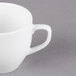A close-up of a Libbey alpine white porcelain cup with a handle on a gray surface.