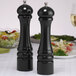 A black pepper mill and salt mill set on a table.