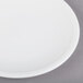A Libbey Alpine White Porcelain Coupe Plate with a white rim on a gray surface.