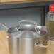 A Vollrath stainless steel pot with a lid on a wooden table.