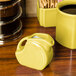 A yellow Fiesta mini disc creamer pitcher on a wood surface.