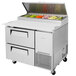 A Turbo Air stainless steel pizza prep table with 2 drawers full of vegetables.