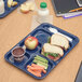 A Carlisle blue 6 compartment tray with a sandwich, apple, and carrot.