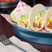 A blueberry polypropylene oval deli server filled with tacos on a table.