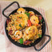 A Lodge carbon steel fry pan with rice, shrimp, and sausage.