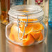A Libbey glass jar filled with orange slices on a counter.
