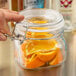 A hand holding a Libbey Garden Jar filled with orange slices.