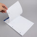 A hand holding a white Ampad writing pad sheet with college ruled lines.