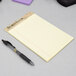 A TOPS narrow ruled canary legal notepad and pen on a table.
