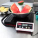 A Rubbermaid digital receiving scale with a bowl of watermelon on it.