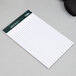 A white TOPS Docket narrow ruled writing pad on a table.