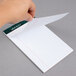 A hand holding a white narrow ruled piece of paper.