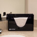 A black San Jamar countertop towel dispenser holding paper towels.