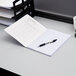 A TOPS composition book and pen on a desk.