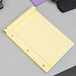 An Ampad yellow lined writing pad on a grey surface.