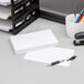 A stack of Oxford white unruled index cards on a desk next to a cup of pens.