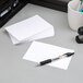 A stack of white Oxford index cards on a desk next to a pen and cup.