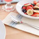 A white table with a Hoffmaster FashnPoint white and blue dishtowel print dinner napkin with a plate of fruit and a spoon on it.