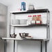 A metal Regency stainless steel double deck overshelf with bowls and bowls on it.