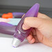 A person using a purple Elmer's glue pen to write on a piece of paper.