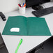 A hunter green Oxford 2-pocket folder on a white desk.