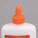 A close up of an Elmer's white glue bottle with an orange cap.