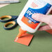 A hand uses Elmer's Glue-All to glue a piece of paper.