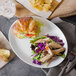 A GET ivory melamine oval platter with chicken salad and a croissant on a table.