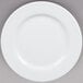 A Tuxton Alaska bright white china plate with a wide rim on a gray surface.