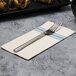 A white napkin with a blue dishtowel print and a fork on a table.
