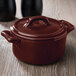 The brown lid of a Bon Chef burnt umber porcelain cocotte sitting on a brown pot.