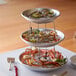 A Choice three tiered seafood tower on a table with crab legs and shrimp.