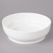 A white Bon Chef curved bowl on a gray surface.