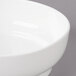 A close-up of a white Bon Chef curved bowl with a rim.