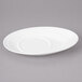 A white Bon Chef slanted oval porcelain saucer with a small hole on a gray surface.