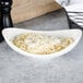 A white porcelain pasta bowl filled with pasta and grated cheese.