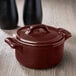 A small burnt umber porcelain cocotte with a lid on a table.