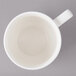 A white porcelain cup with a handle on a gray surface.