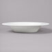 A Bon Chef white bone china wide rim soup bowl on a gray surface.