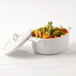 The white lid of a Bon Chef white porcelain cocotte over a pot of vegetables.