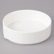 A white Bon Chef porcelain soup bowl with stacked lines on a gray surface.
