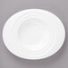 A white porcelain oval pasta bowl on a gray surface.