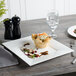 A Bon Chef white bone china square plate with a pastry on it on a table.