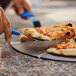 A person using a GI Metal blue triangular pizza server to cut a slice of pizza.