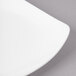 A close-up of a white Bon Chef porcelain bread and butter plate with a curved edge.