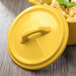 A yellow Bon Chef cocotte lid on a white surface.