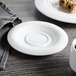 A white Bon Chef porcelain demi saucer on a white surface with food on it.
