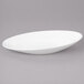 A white oval shaped bowl on a gray surface.