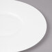 A close-up of a Bon Chef white bone china plate with a wide rim.